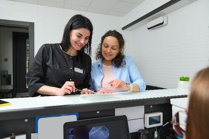 Practice manager and patient at reception desk
