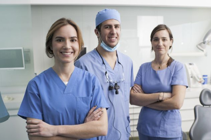 Three dentists stood in dental appointment room